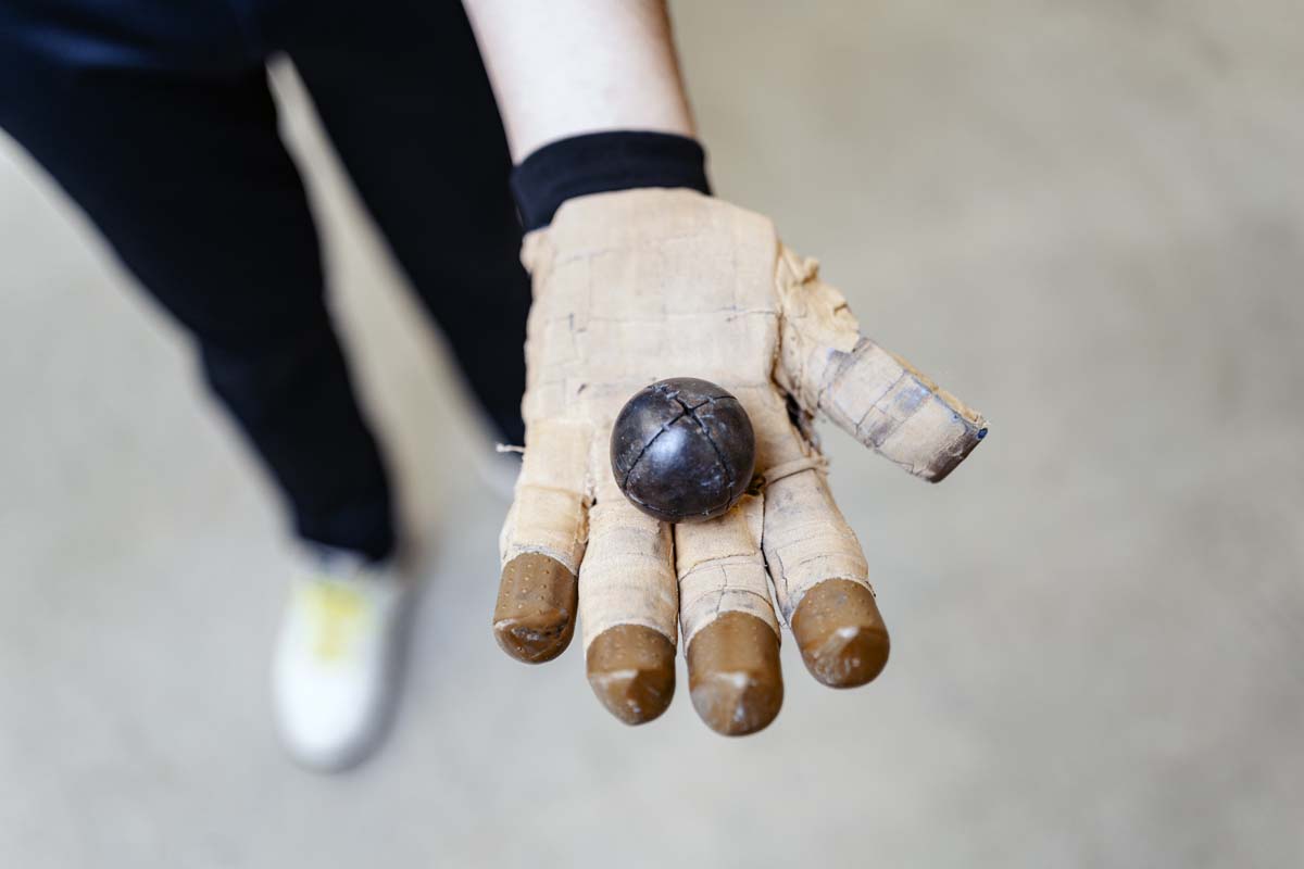 Imagen de una mano con un guante y una pelota del trinquet, deporte de pelota valenciana